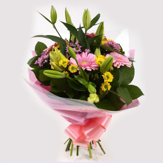Colourful hand-tied bouquet with lilies, gerberas and green foliage