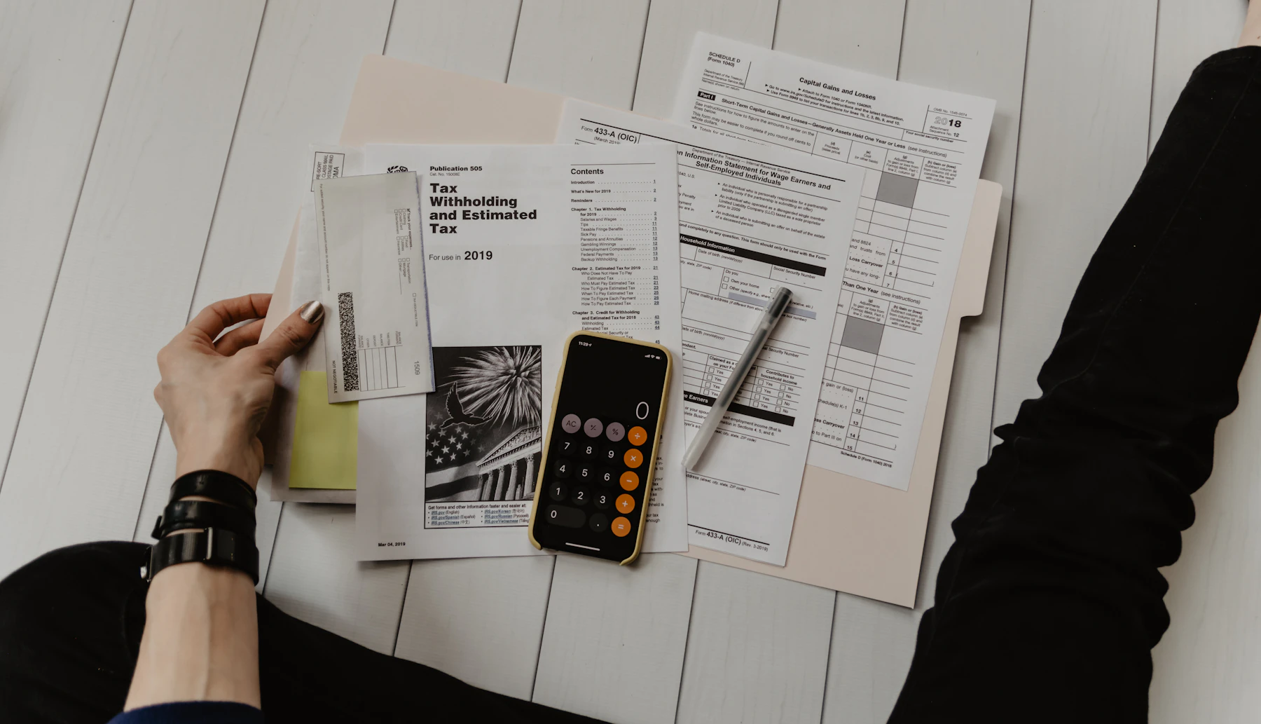 Person using a calculator beside personal-finance paperwork