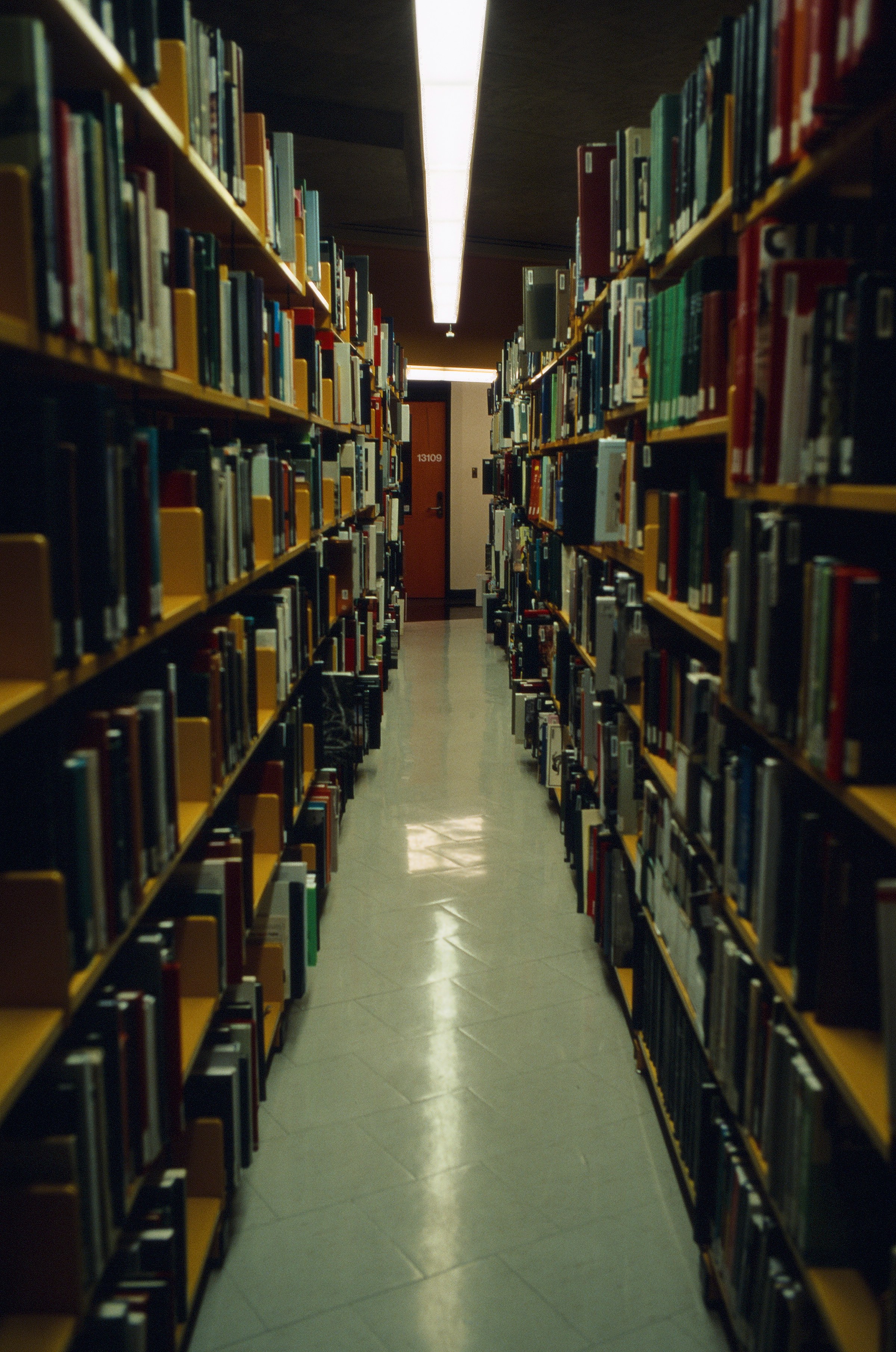 Narrow aisle between tall shelves densely filled with second-hand books
