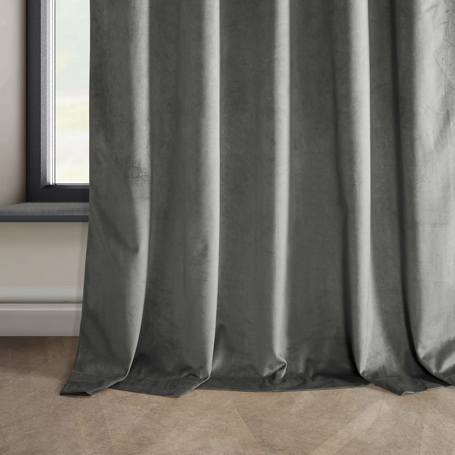 Floor-length gray velvet blackout curtains hanging beside a window