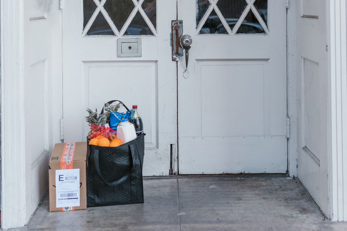 Grocery bag and delivery parcel waiting at a front door