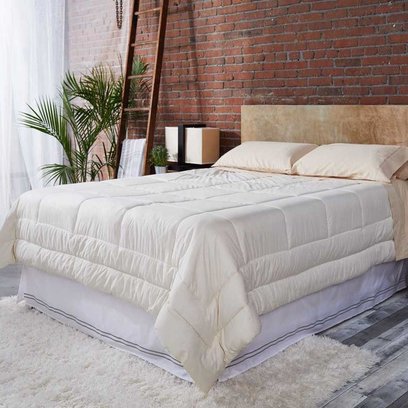 White Sleep and Beyond natural wool comforter arranged on a bed in a bright brick-walled bedroom