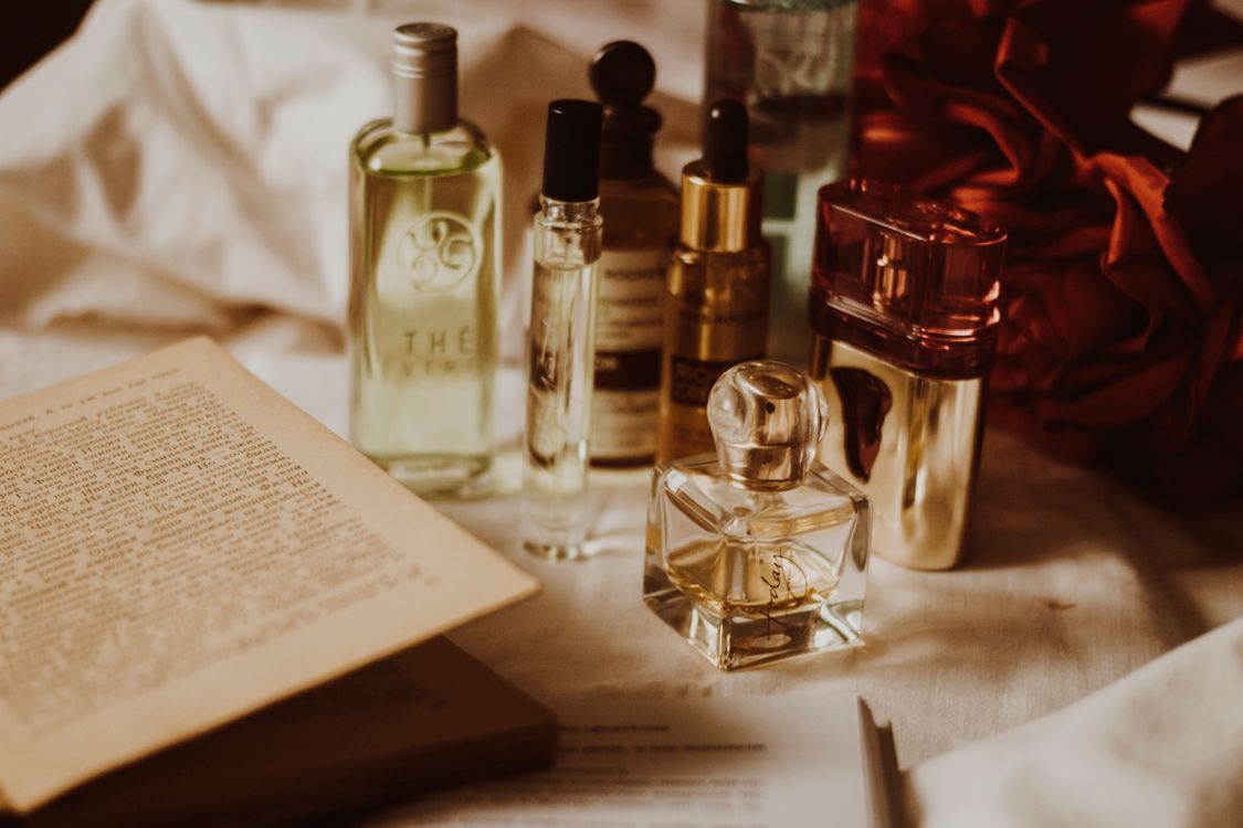 Assorted perfume bottles arranged beside a book and rose