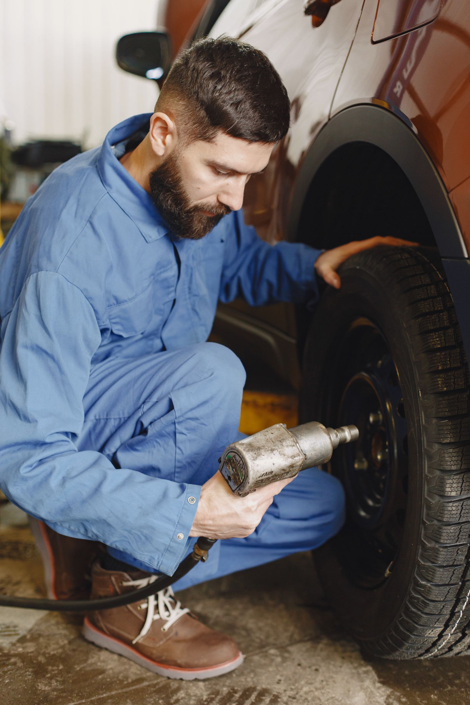 Mechanic using an impact wrench on a car wheel in a workshop