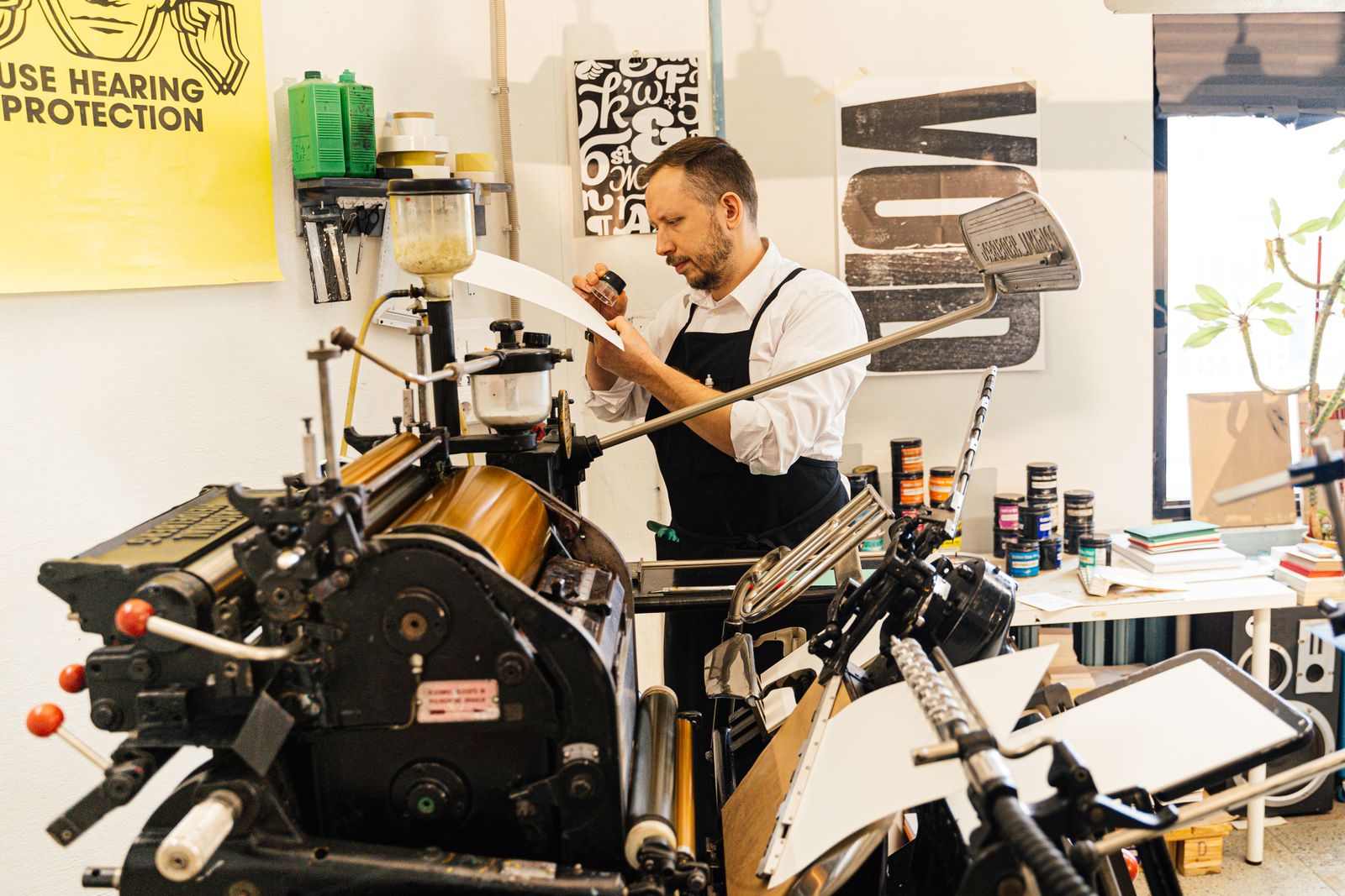 Printmaker operating a press inside a busy workshop