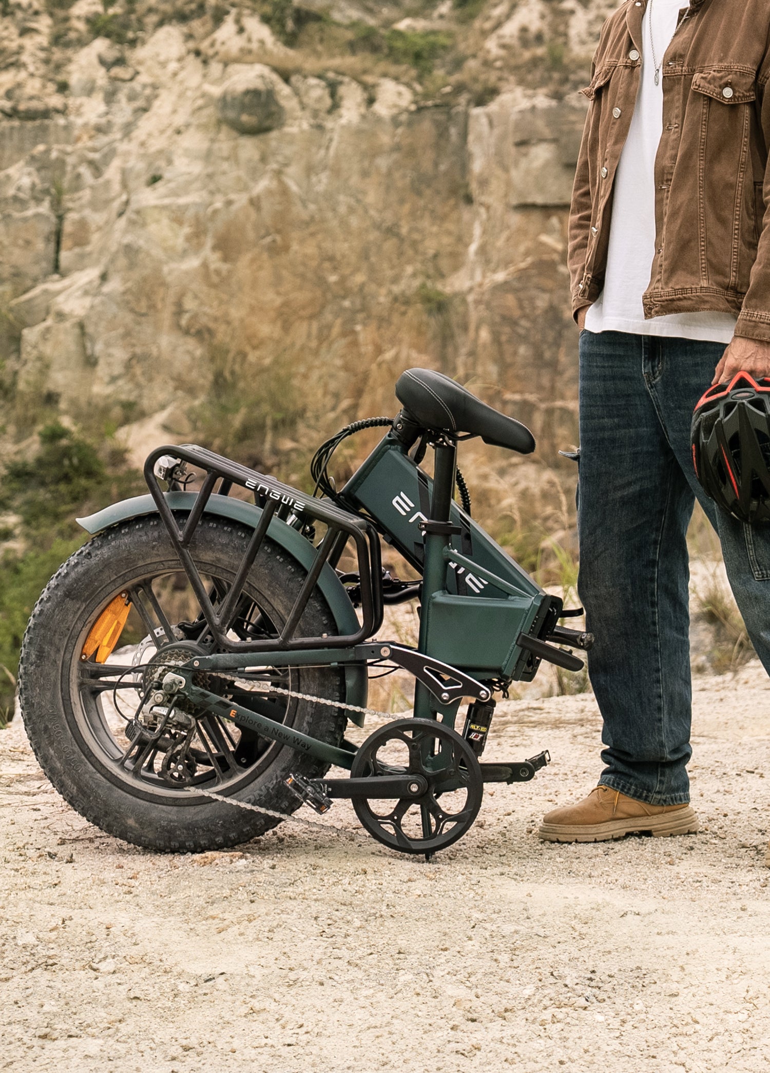 Person standing beside a folded dark green Engwe electric bicycle outdoors