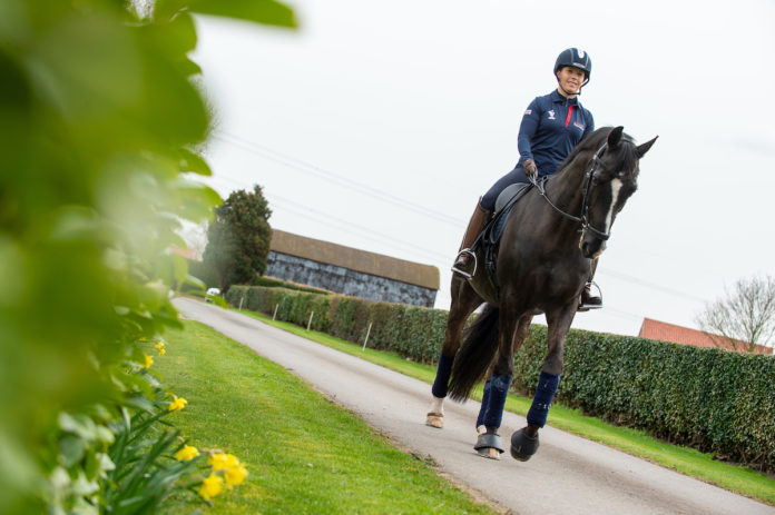 Equestrian rider wearing a helmet while riding a black horse outdoors
