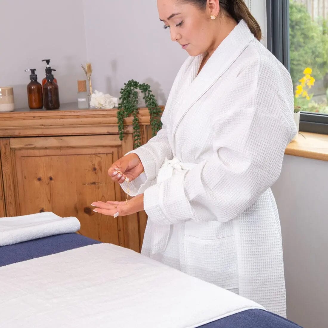 Spa worker in a white robe arranging a cover on a treatment couch