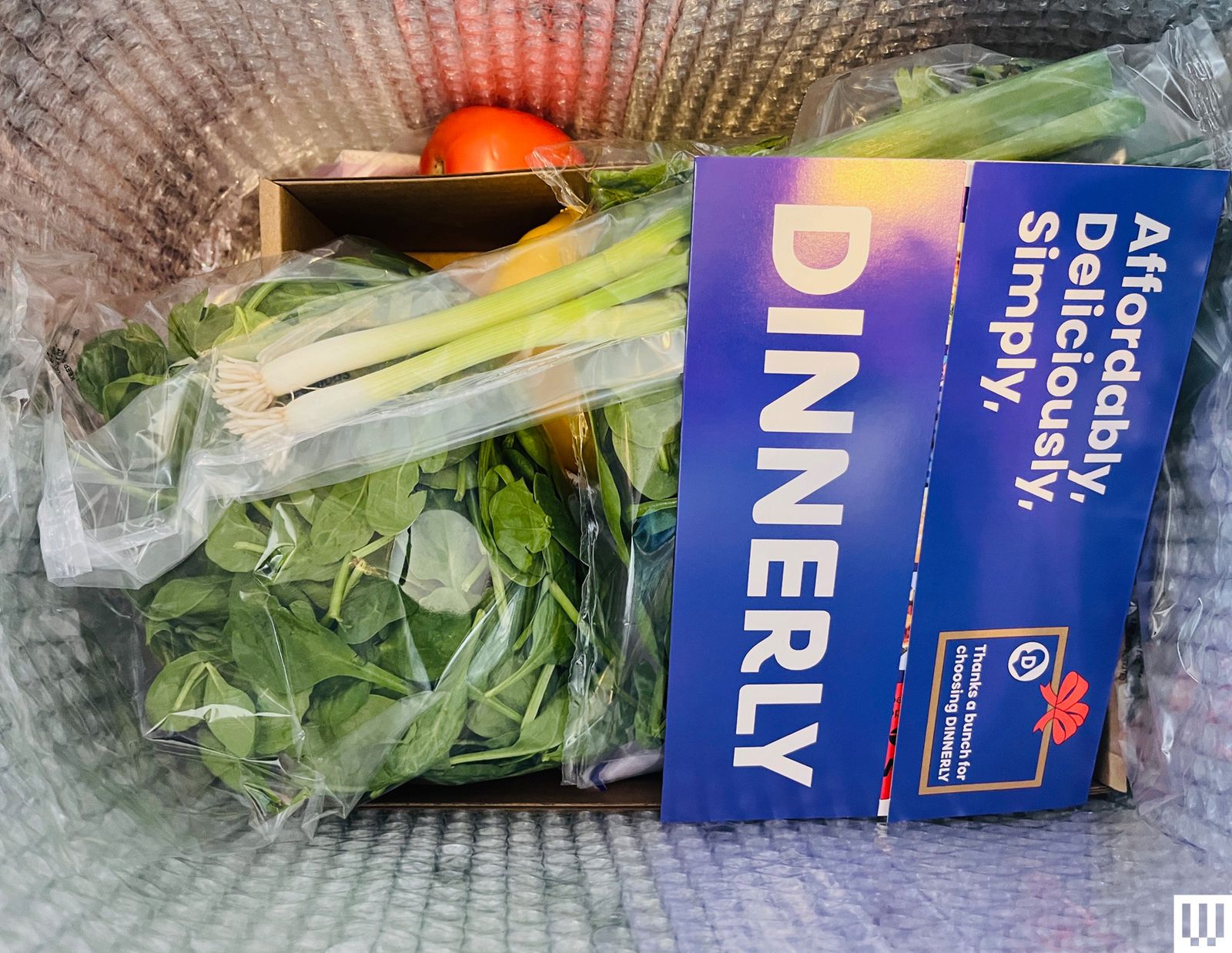 Fresh vegetables and ingredients packed inside an open Dinnerly meal-kit box