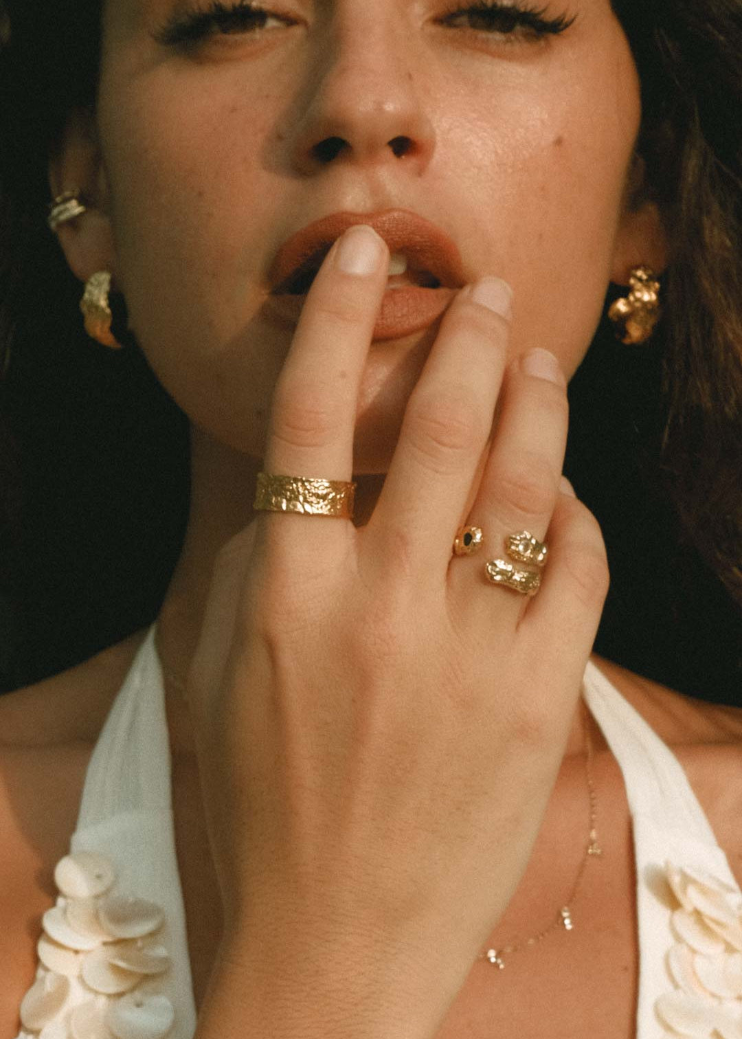 Woman wearing gold rings, earrings and a fine necklace from Aaria London