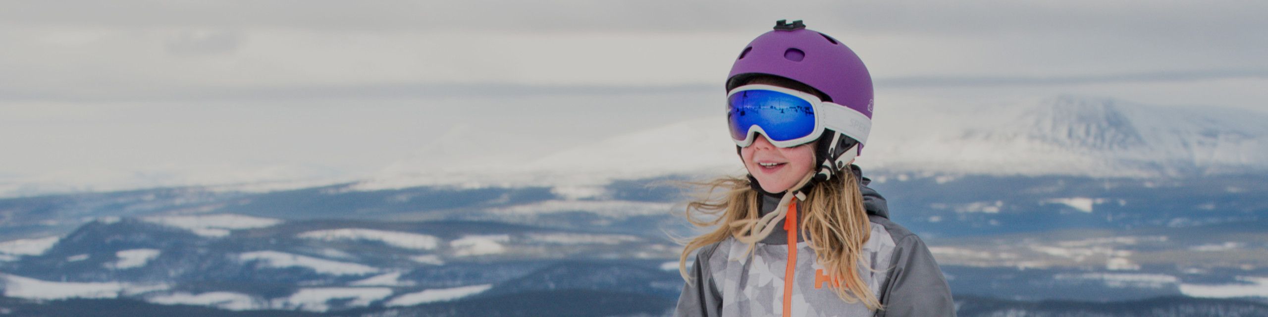 Child wearing ski helmet, goggles and jacket in the snow at AktivWinter