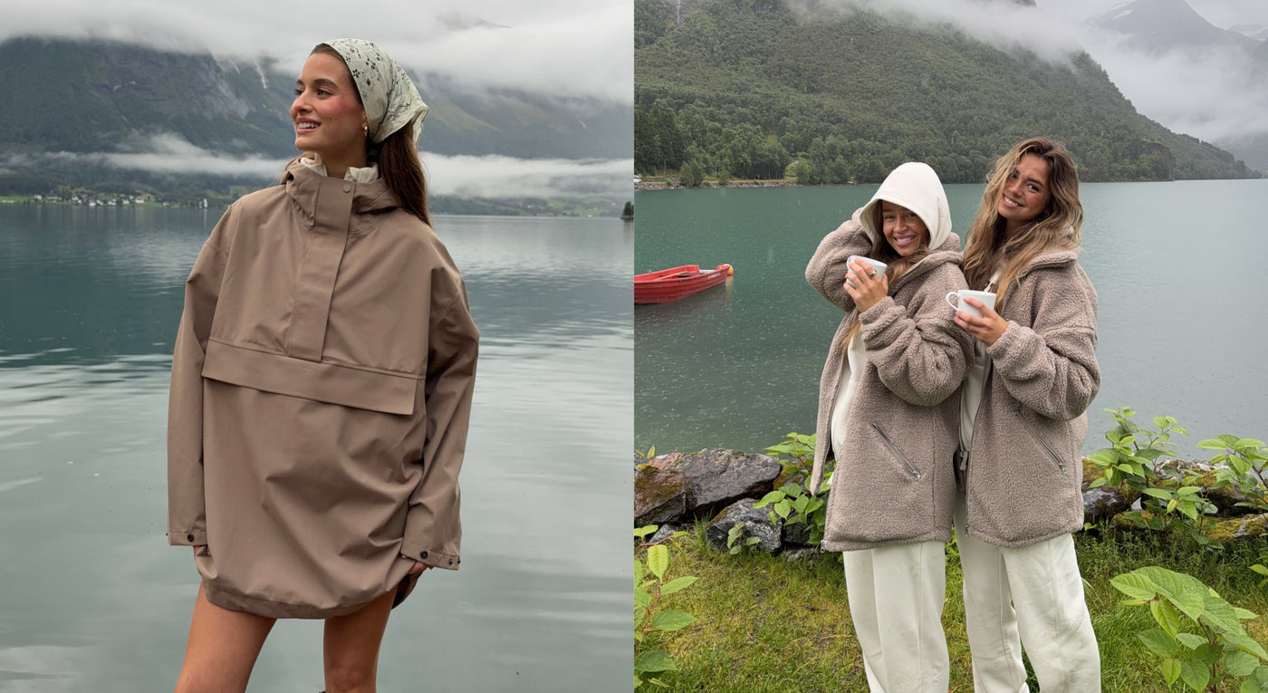 Three women wearing neutral outdoor activewear beside a mountain lake