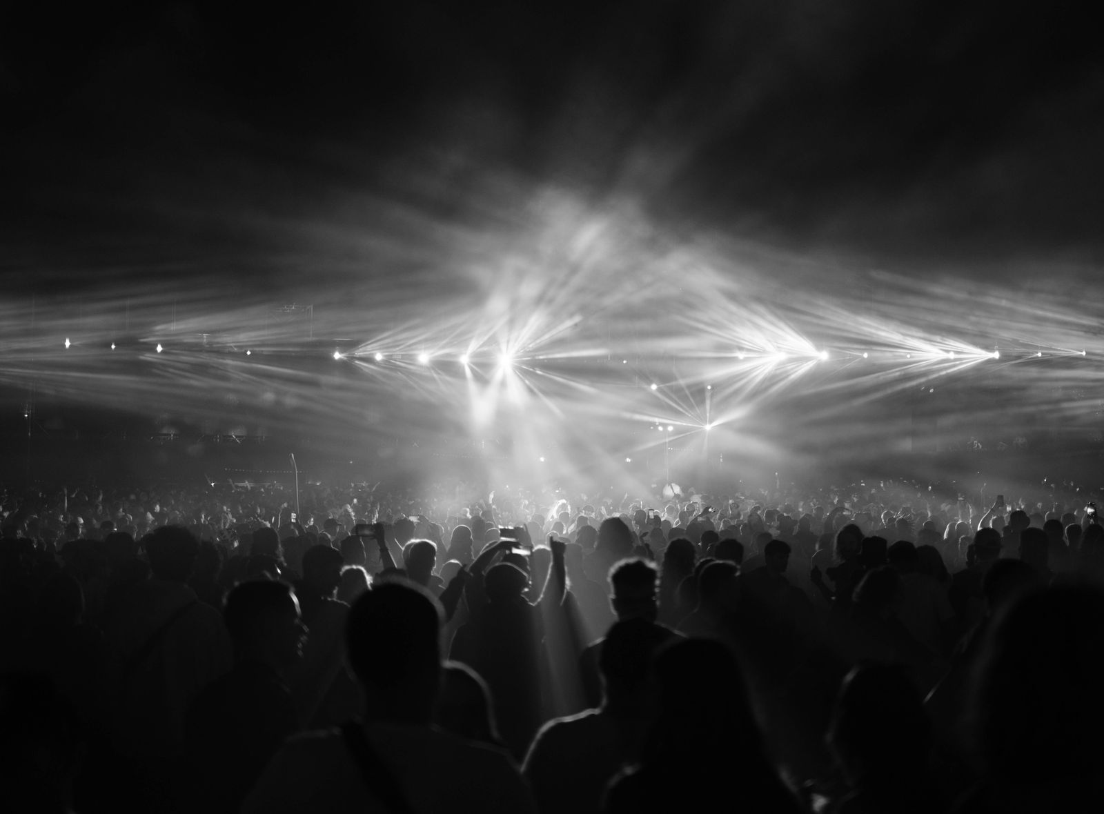 Concert audience facing bright stage lights in a dark indoor venue