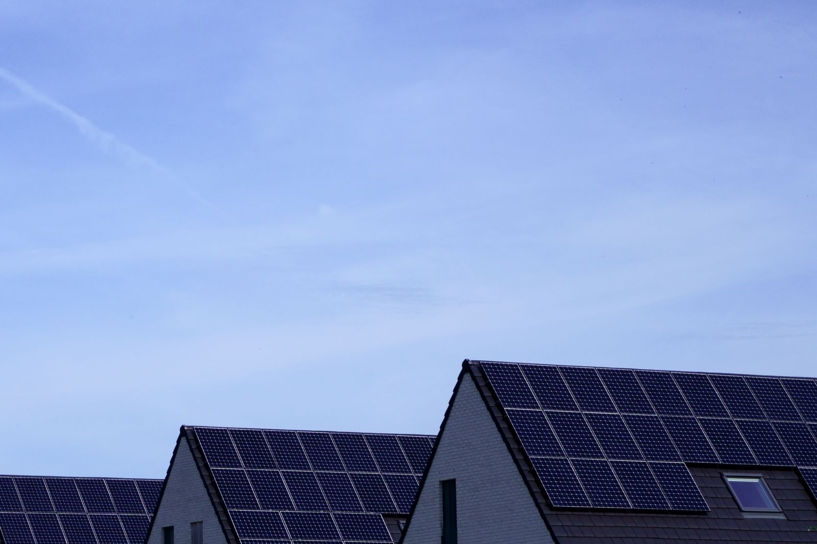 Solar panels installed across the roofs of modern houses under a blue sky