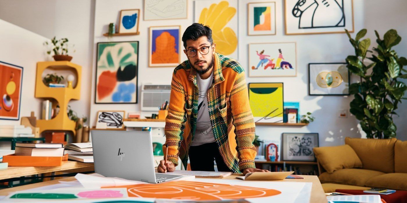 Designer working at a desk with an HP laptop in a colourful home studio