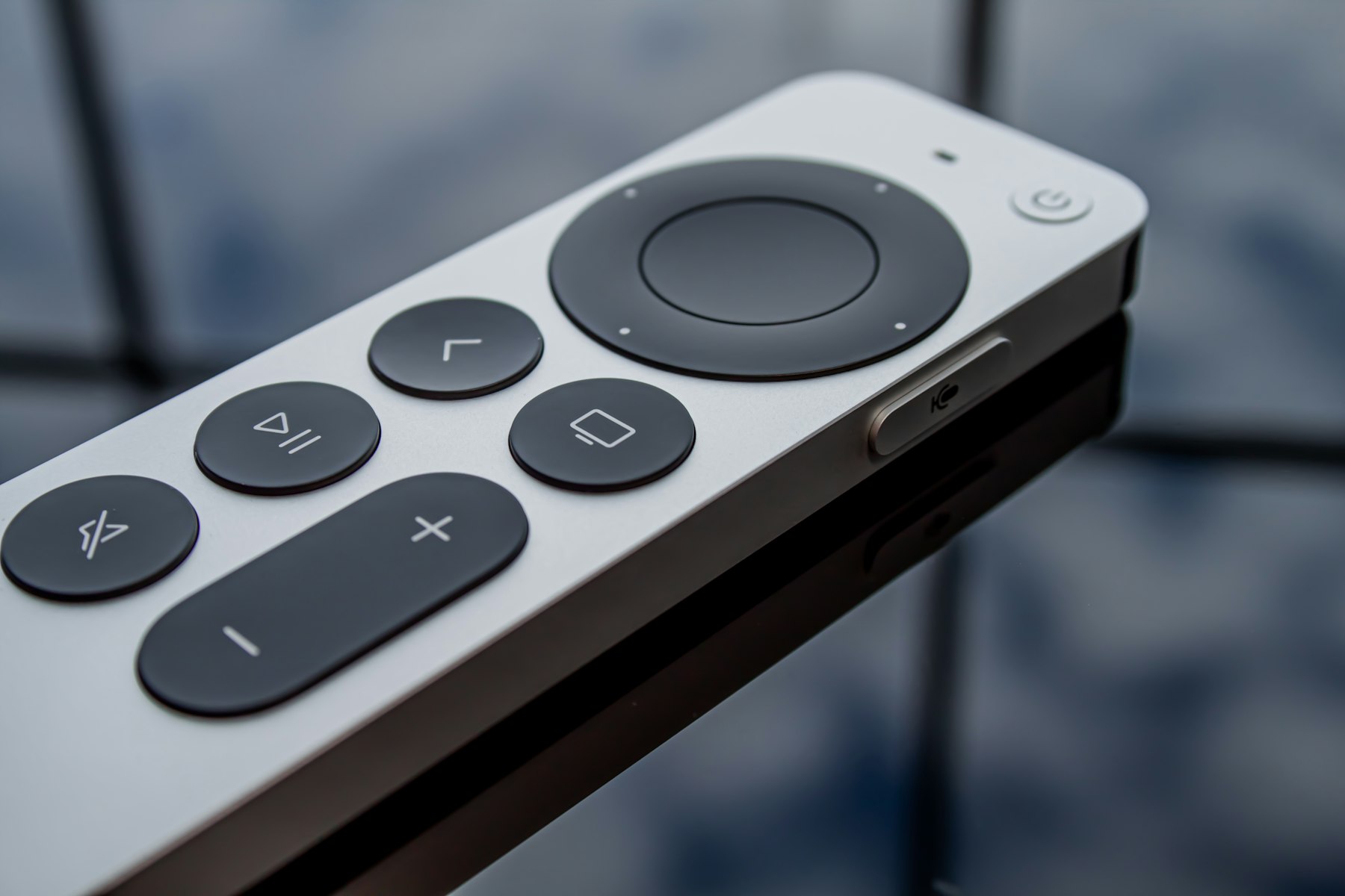 A television remote control resting on a dark surface