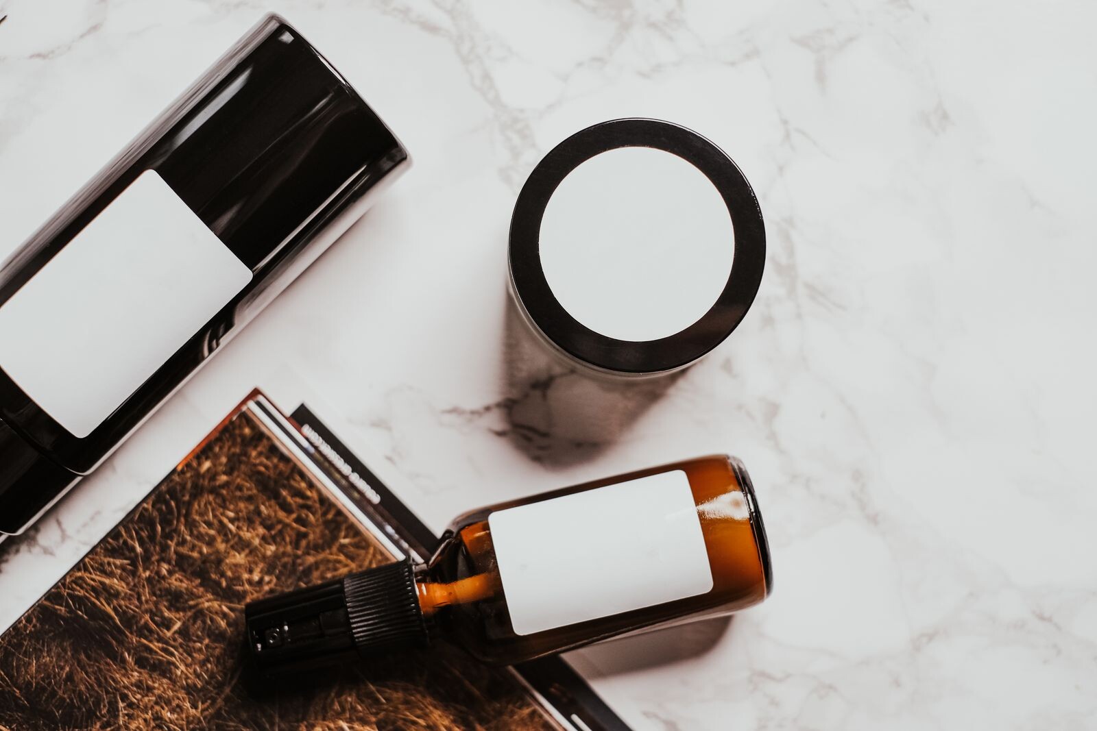 Amber skincare bottles and a cream jar arranged on white marble