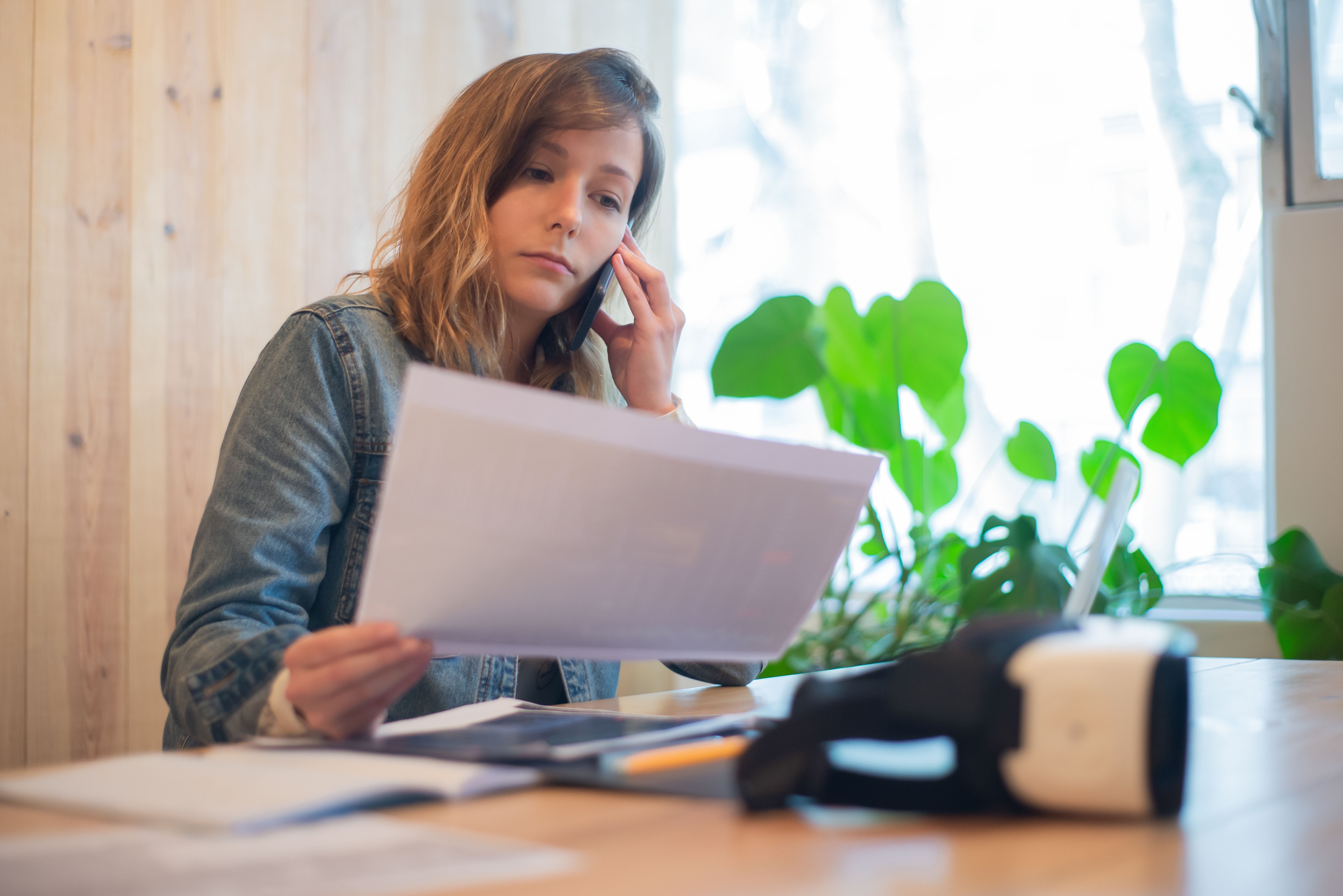 Woman reviewing paperwork while speaking on the phone at a desk