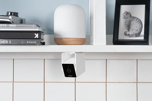 White Petcube Cam mounted below a shelf in a bright home interior