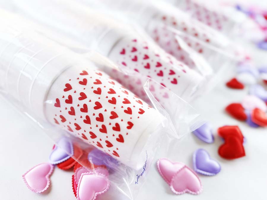 Clear party cups printed with red hearts and surrounded by pink, red, and purple heart decorations
