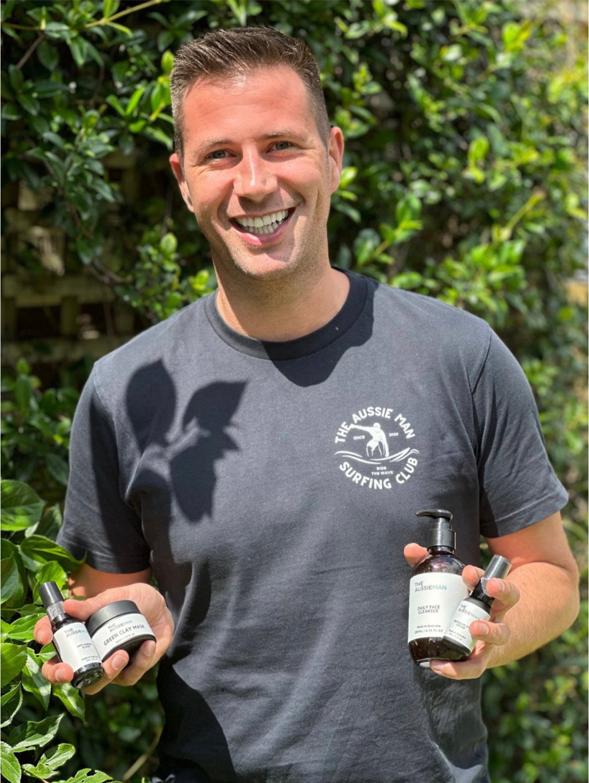 Man outdoors holding a selection of men's skincare products