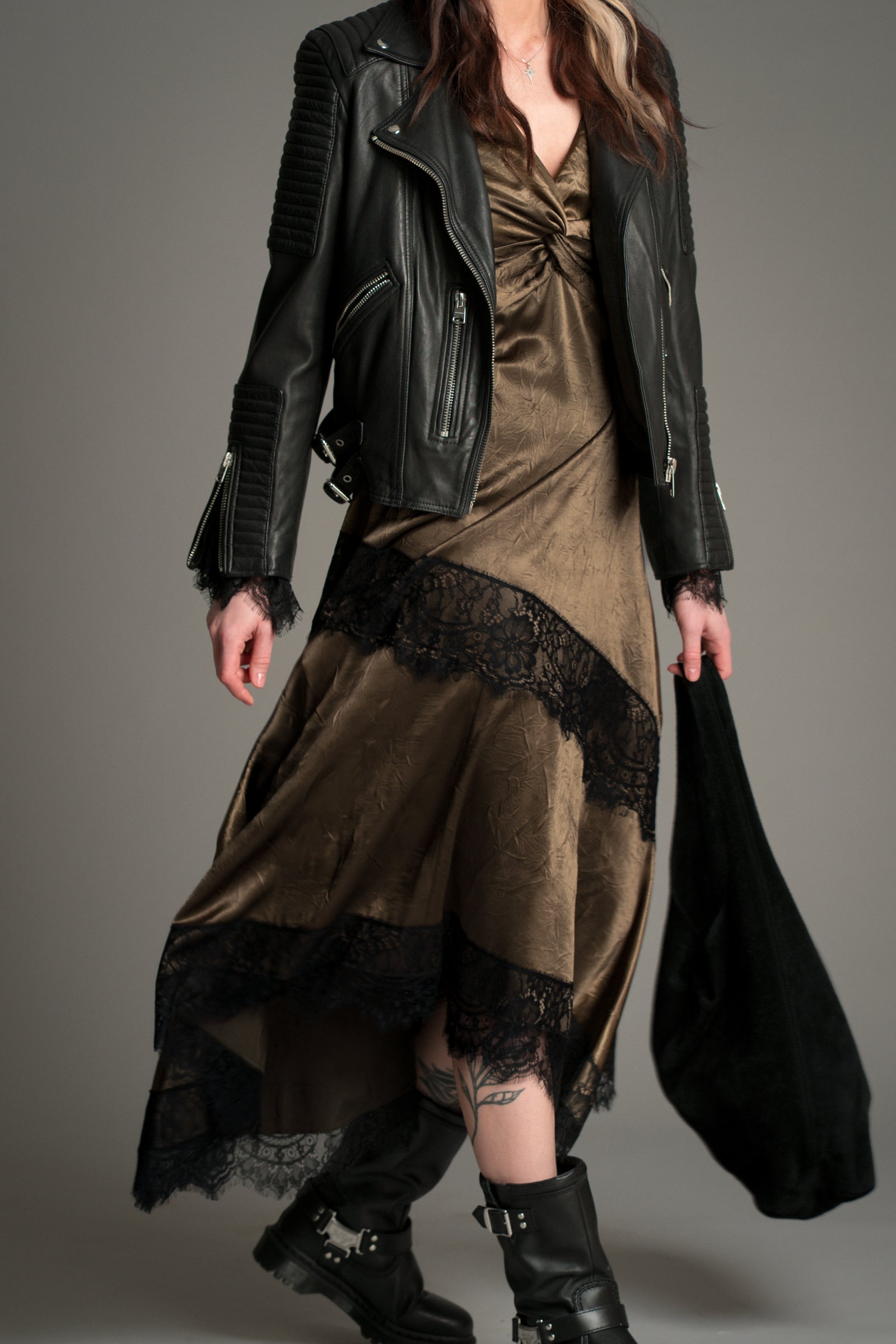 Model wearing a brown satin and black lace midi dress with a black leather jacket.