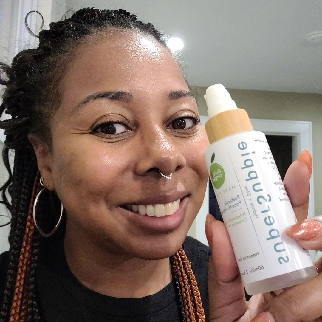 Woman holding a Pure and Cimple skincare serum bottle beside her face