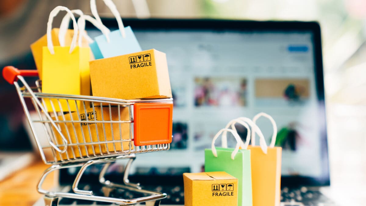 Miniature shopping carts filled with colourful bags in front of an online marketplace