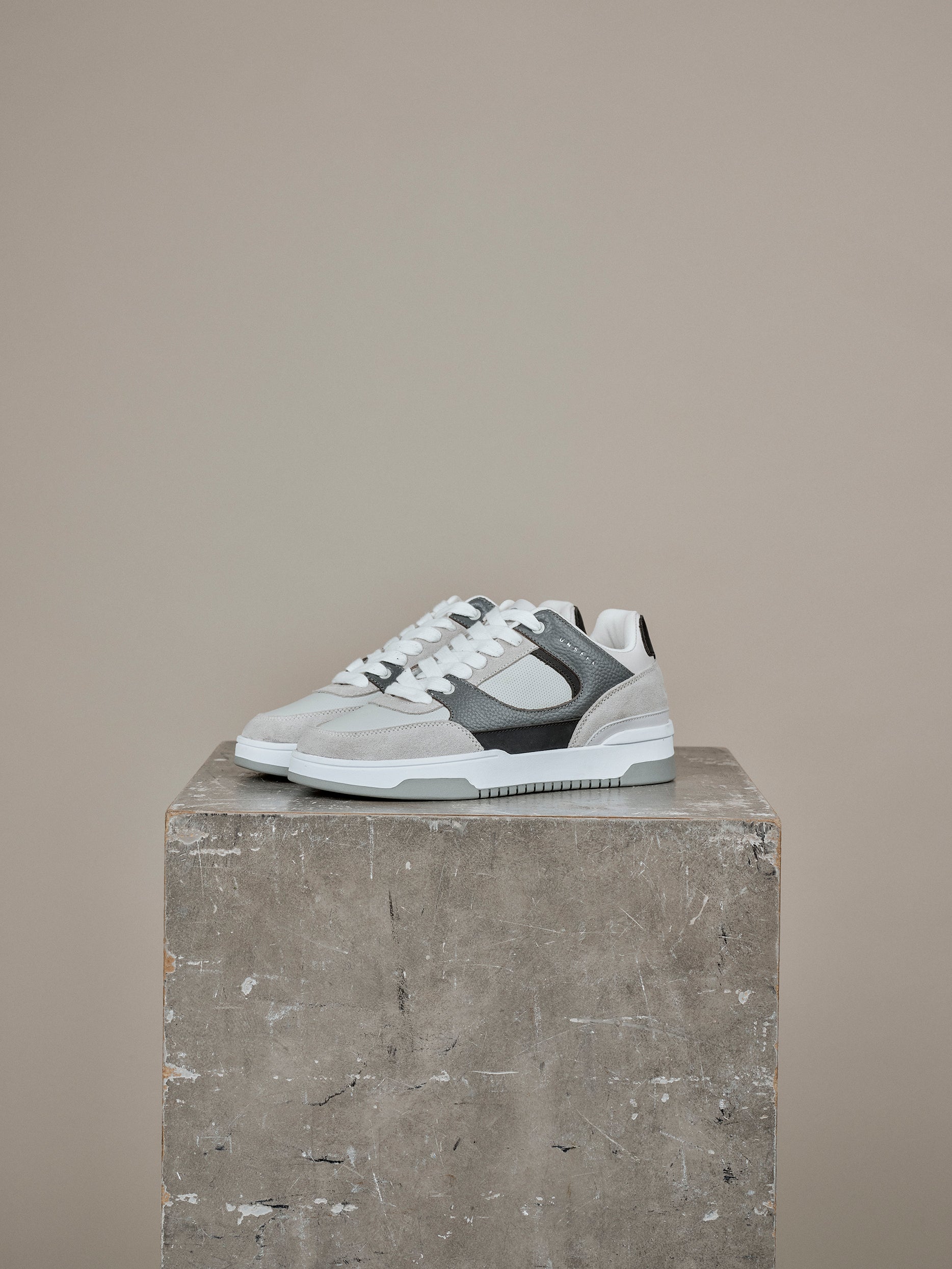 Grey and white Unseen Footwear Regent trainer on a neutral backdrop