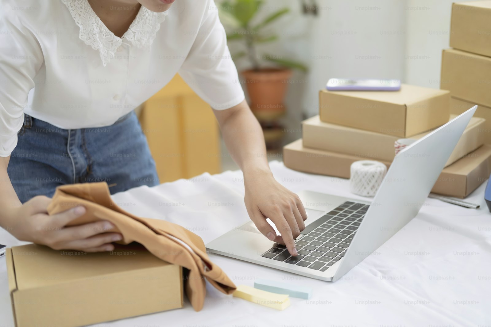 Online seller checking an item beside open cardboard shipping boxes