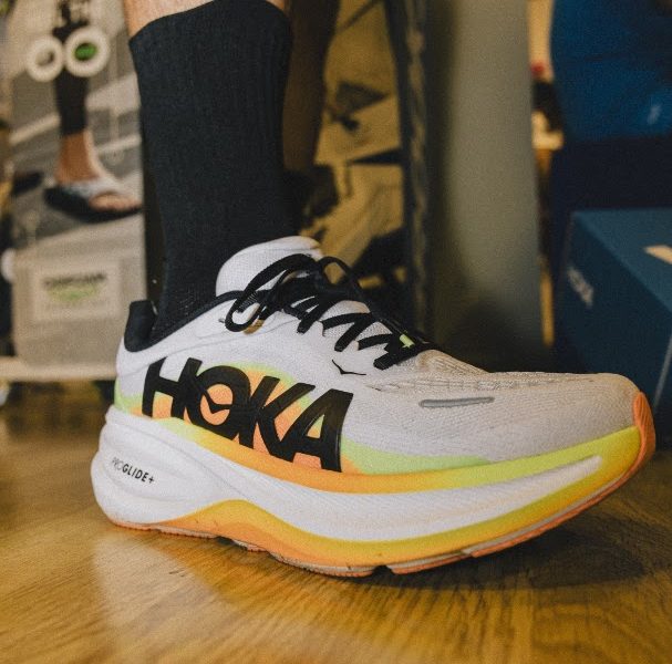 Close-up of a runner wearing a white Hoka running shoe inside a sports shop
