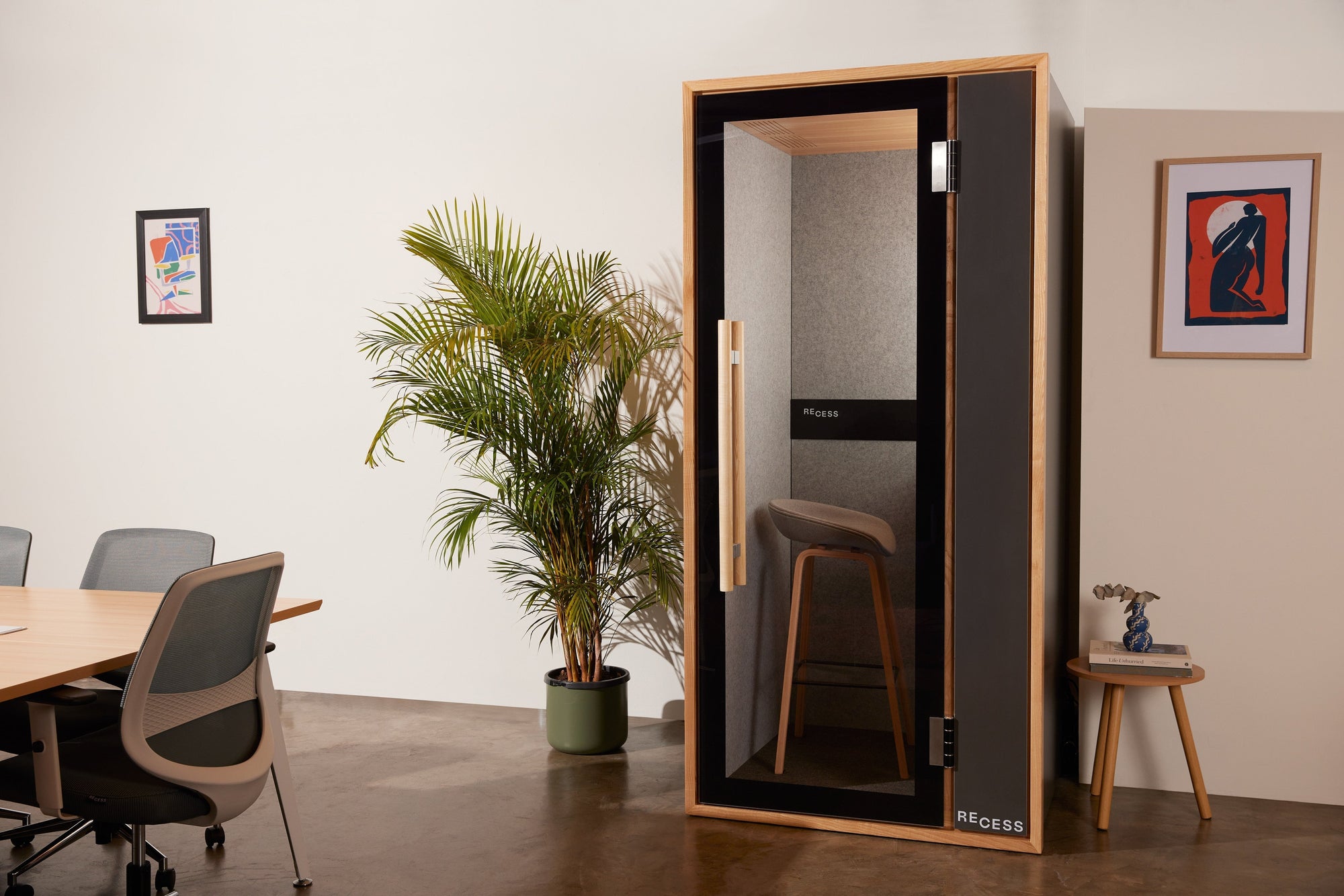 Freestanding acoustic work booth beside desks in a modern office