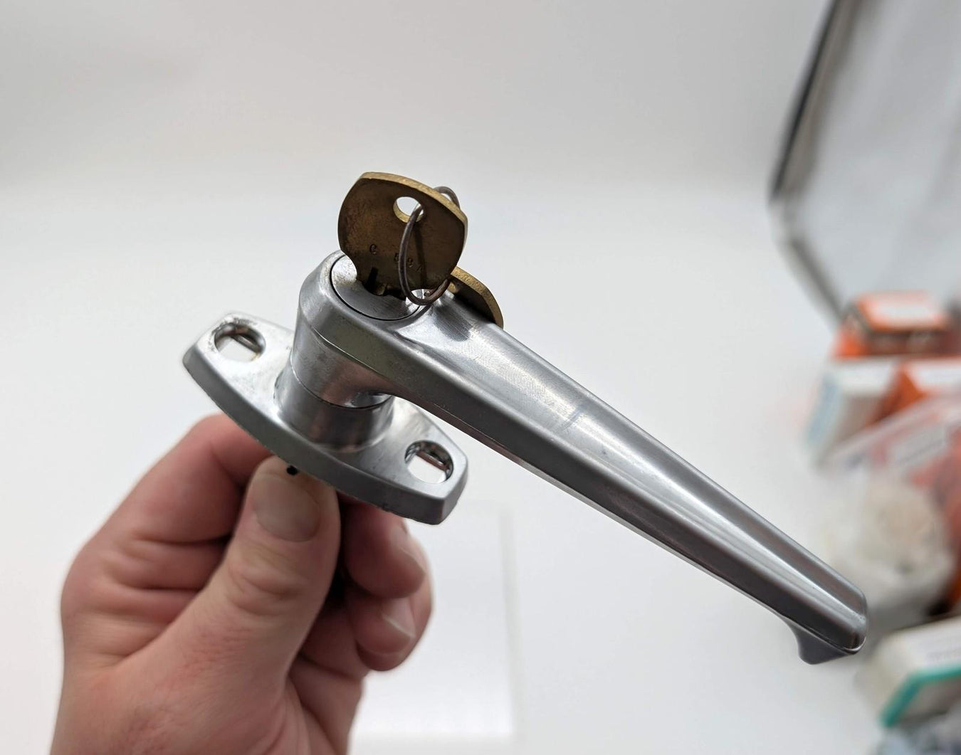 A locksmith works on a metal lock mechanism with a hand tool