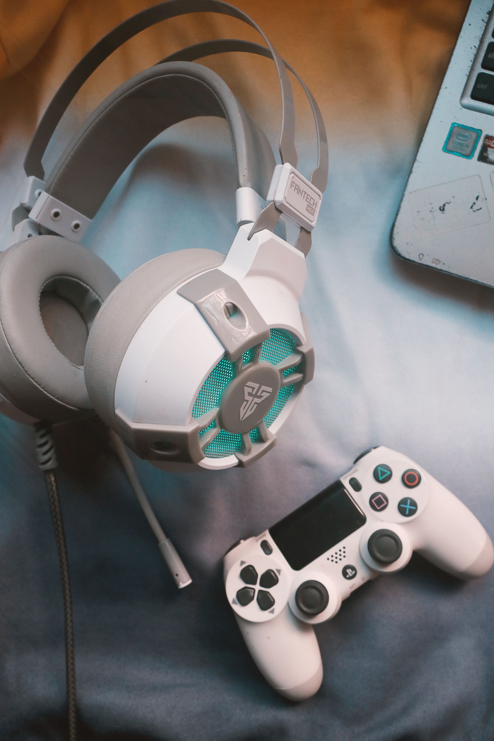 Gaming headset beside a controller and laptop on a desk