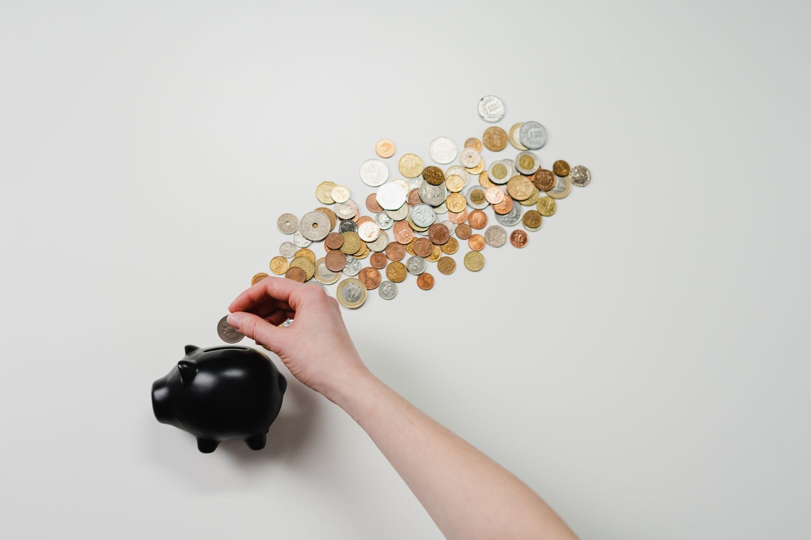 Person placing a coin into a piggy bank