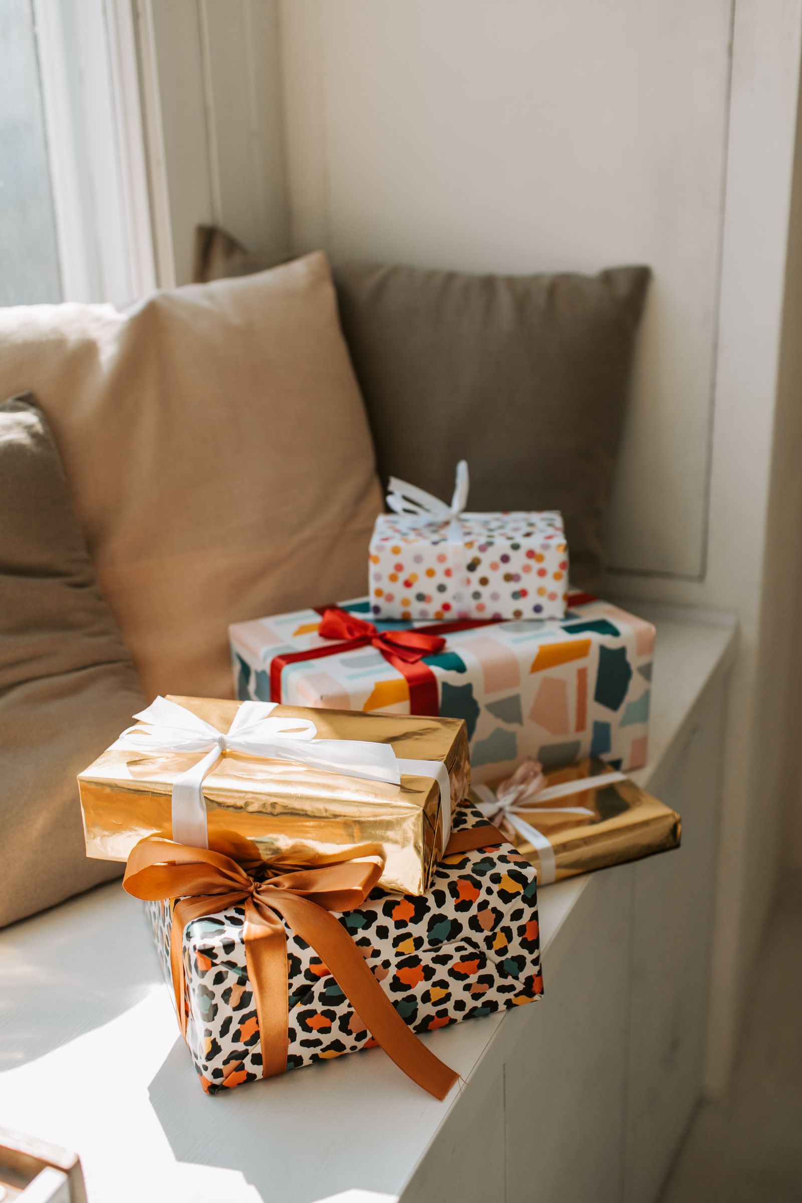 Colorfully wrapped gift boxes arranged on a cushioned window seat